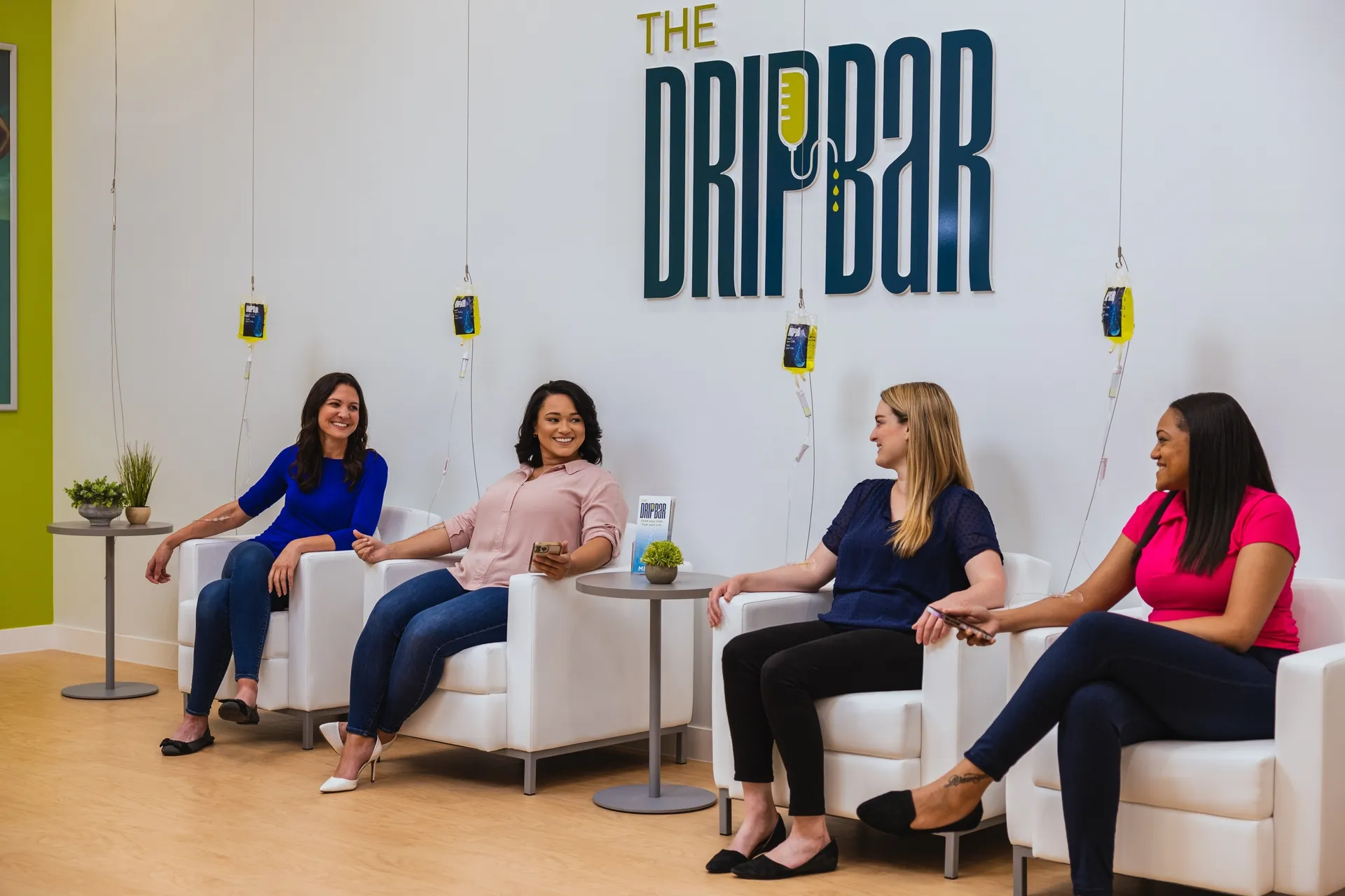 Four clients on white sofas receiving IV drips